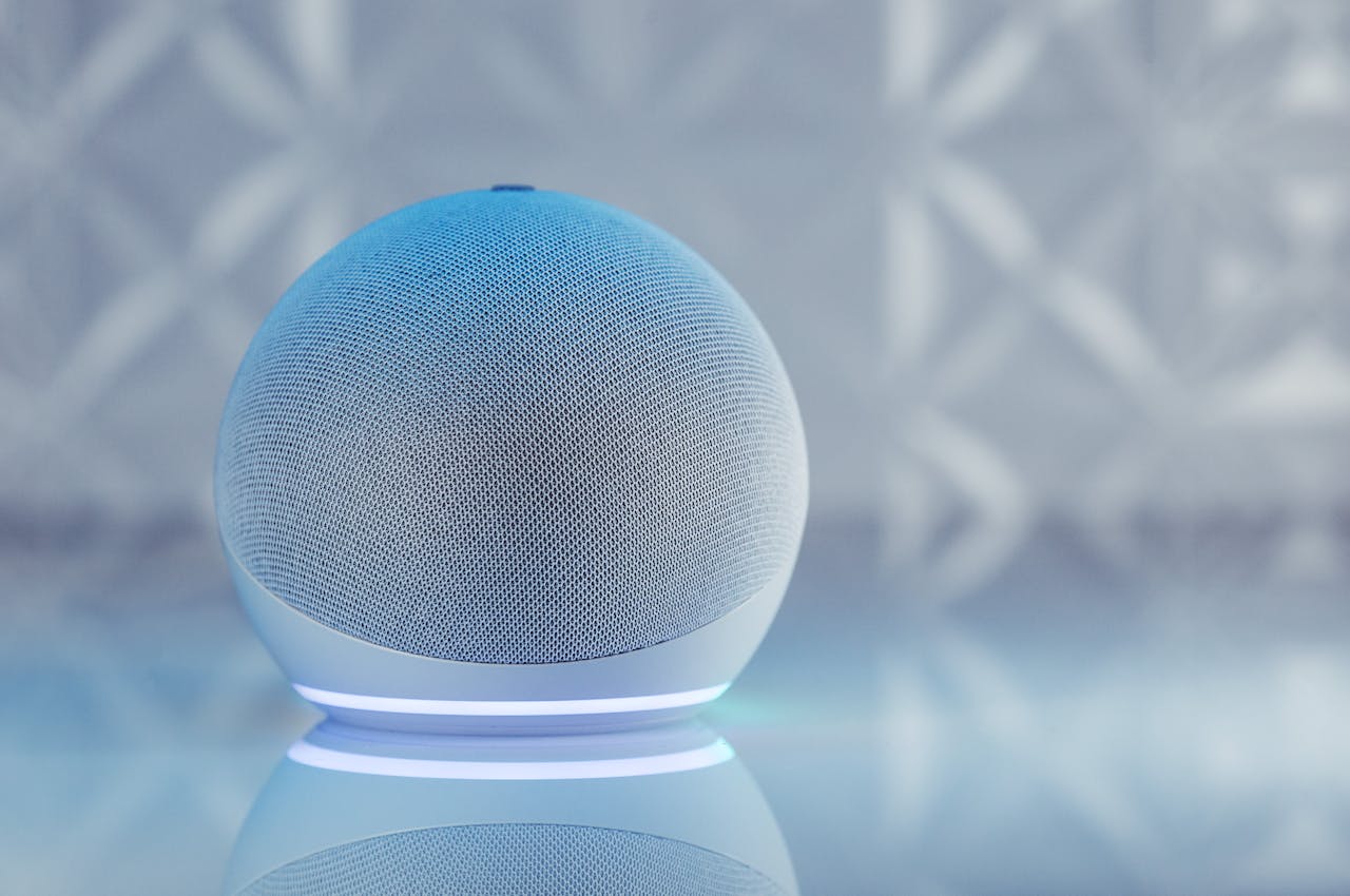 home-img A sleek smart speaker with neon glow on reflective surface, showcasing modern technology.