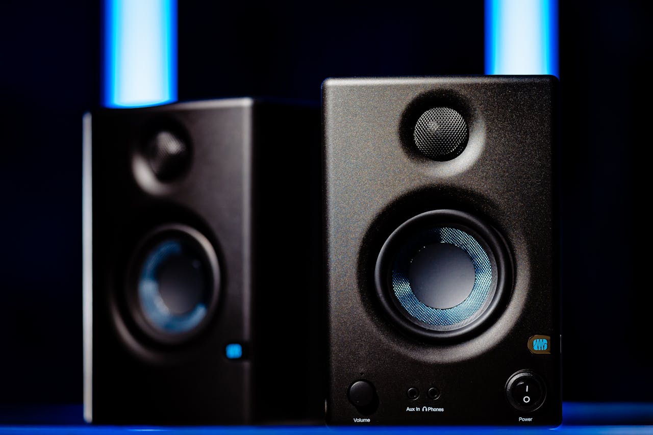 gallery-01 Close-up of modern black loudspeakers with blue accents in a studio setting.